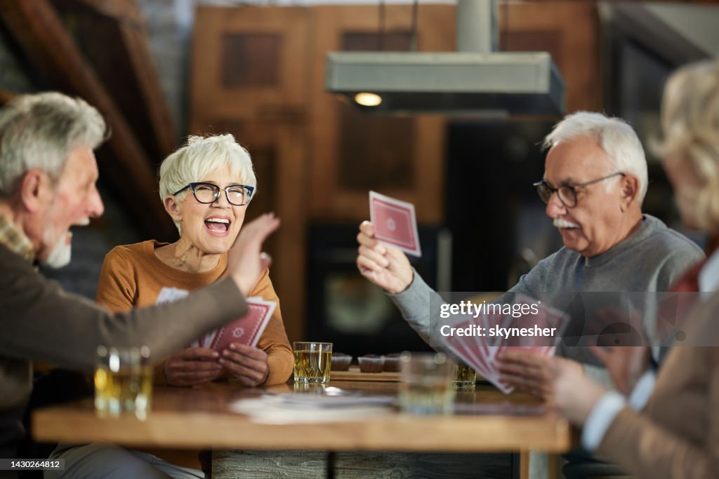 Group of happy seniors having fun while playing cards at home.