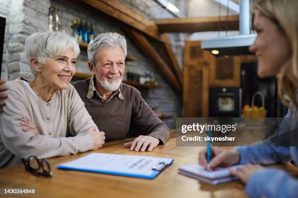 glückliches älteres paar, das mit dem versicherungsagenten zu hause spricht. - lebensversicherung stock-fotos und bilder