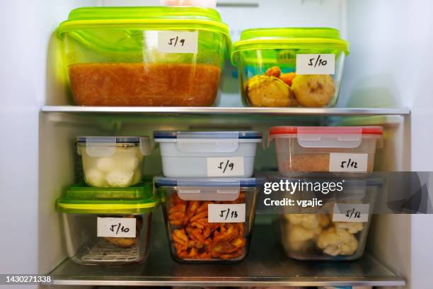 food leftovers packaged in boxes inside a home fridge - leftovers stockfoto's en -beelden