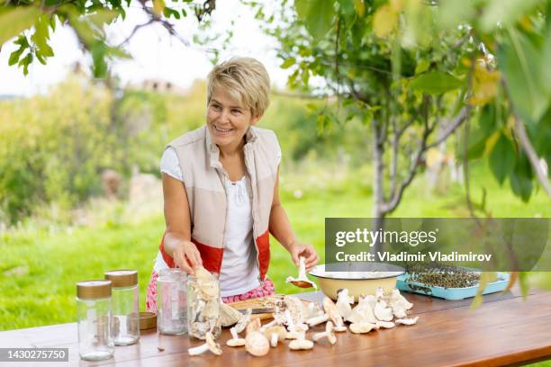 a middle aged woman is reserving organic mushrooms in jars - jäst bildbanksfoton och bilder