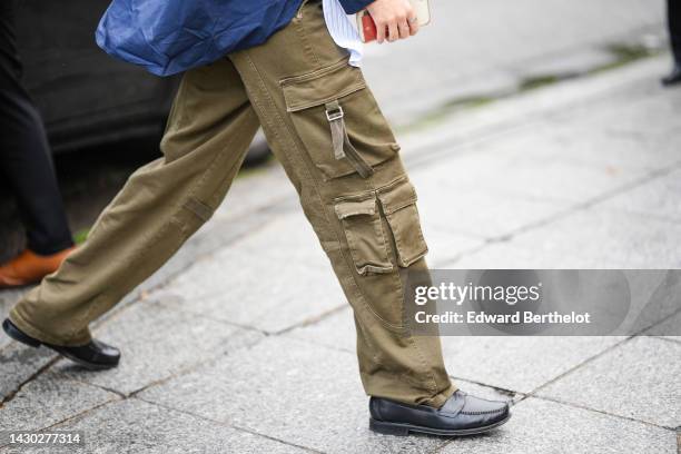 Guest wears khaki cargo pants, black shiny leather laofers , outside Botter, during Paris Fashion Week - Womenswear Spring/Summer 2023, on September...