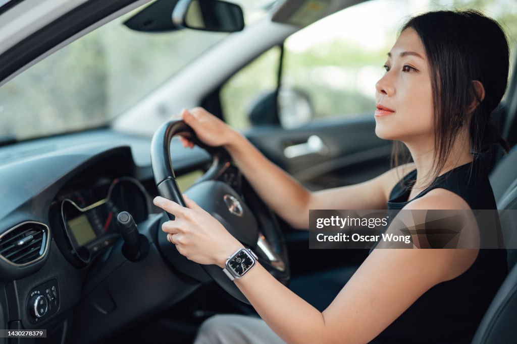 Side view of young Asian woman driving a car