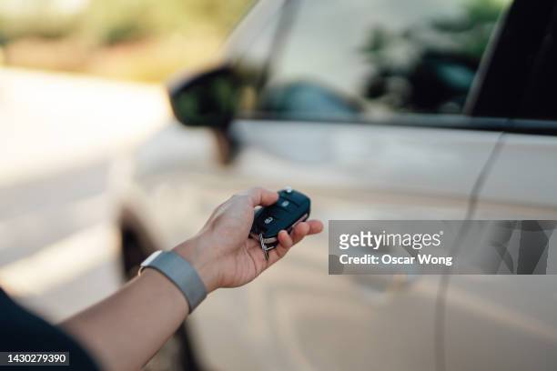 female hand unlocking car with electronic car key - auto mieten stock-fotos und bilder