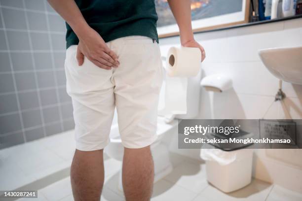 man holding toilet tissue roll in bathroom looking at loo - kot stock-fotos und bilder