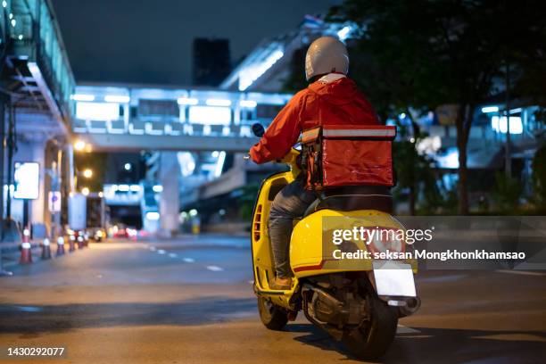 delivery man driving a scooter - motorbike delivery at night stock pictures, royalty-free photos & images
