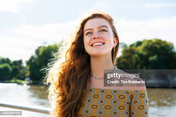 woman smiling looking up next to river - cutis claro fotografías e imágenes de stock