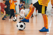 Football futsal training for children. Soccer training drill. Indoor soccer young player with a soccer ball in a sports hall. Player in yellow uniform. Sport background