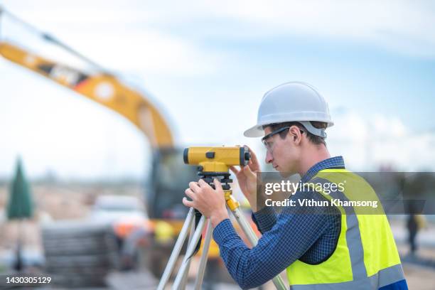 male engineer and survey equipment working at construction site. - ingeniería civil fotografías e imágenes de stock