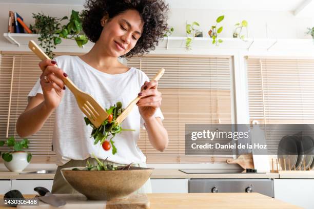happy young multiracial woman mixing bowl of fresh salad. copy space.healthy lifestyle - cookery foto e immagini stock