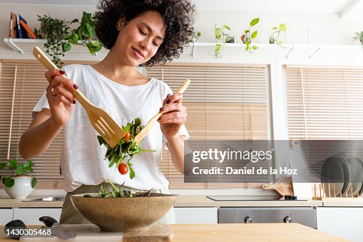 Happy young multiracial woman mixing bowl of fresh salad. Copy space.Healthy lifestyle Happy young multiracial woman mixing bowl of fresh salad. Copy space.Healthy lifestyle