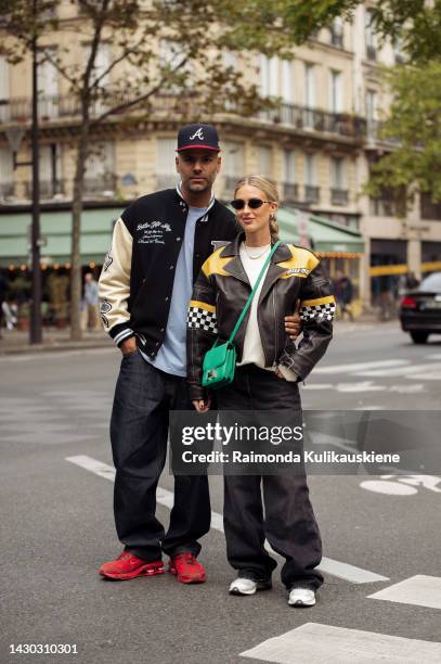 Emili Sindlev wearing black wide jeans, a white shirt, a black and yellow leather racers jacket, and a green Hermes bag, and Mads Emil Grove Møller...