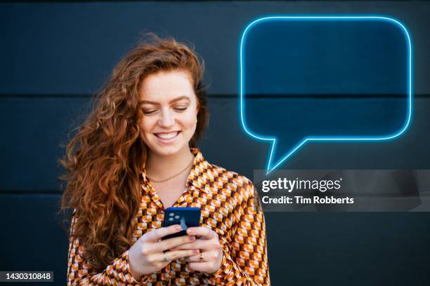woman using smart phone with neon speech bubble - neon speech bubble stock-fotos und bilder