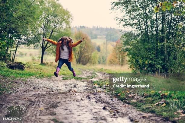 teenager-mädchen, das über herbstpfützen springt - puddle stock-fotos und bilder