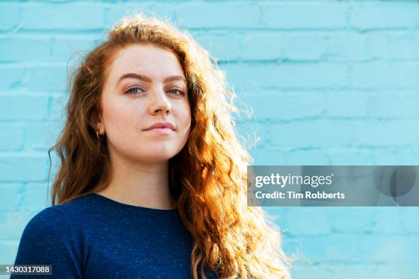 portrait of woman next to blue back wall - heroes stock-fotos und bilder