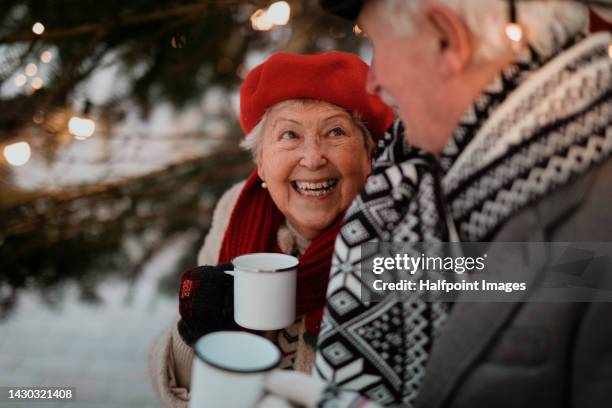 cheerful senior couple enjoying outdoor christmas market, drinking punch. - old man woman christmas stock pictures, royalty-free photos & images