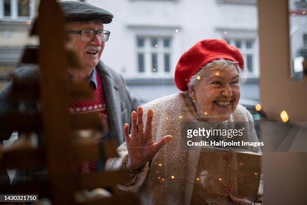 senior couple shopping christmas gifts, looking in shop showcase. - old man woman christmas stockfoto's en -beelden