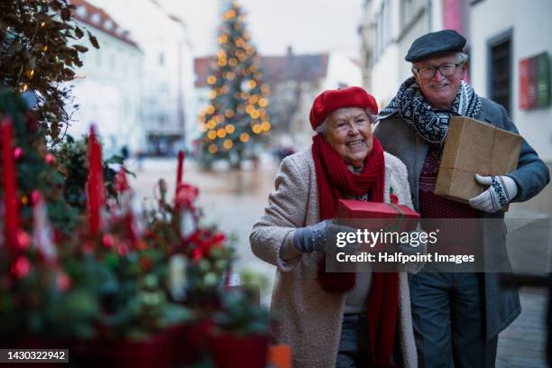 senior couple shopping gifts at christmas market. - old man woman christmas stock pictures, royalty-free photos & images