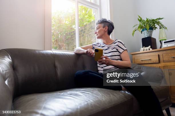 adulto maturo che guarda fuori dalla finestra - menopausa foto e immagini stock