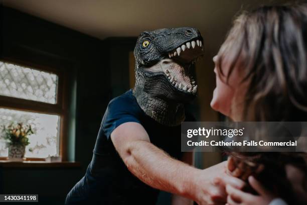 playful image of a father playing with his little girl. he wears a rubber dinosaur mask. she squeals with delight. - tickle monster stock pictures, royalty-free photos & images