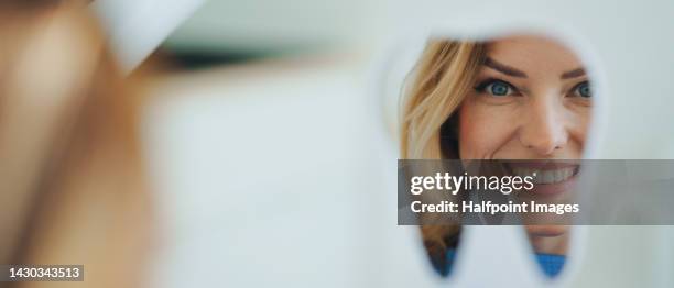 happy patient looking at her teeth in mirror. - implante imagens e fotografias de stock