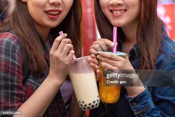 close-up of two asian women enjoy bubble milk tea and looking at camera - bubble tea stock pictures, royalty-free photos & images