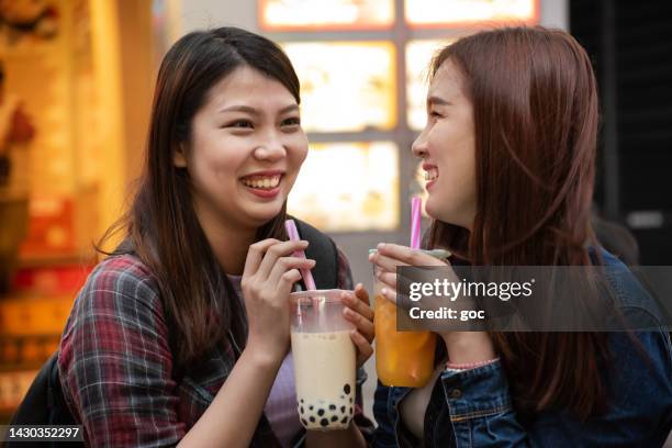 two joyful asian women enjoy bubble milk tea together - bubble tea stock pictures, royalty-free photos & images