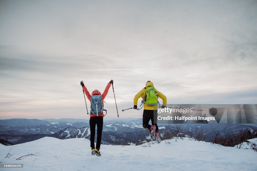 Excited senior couple enjoying view from mountain peak, jumping.