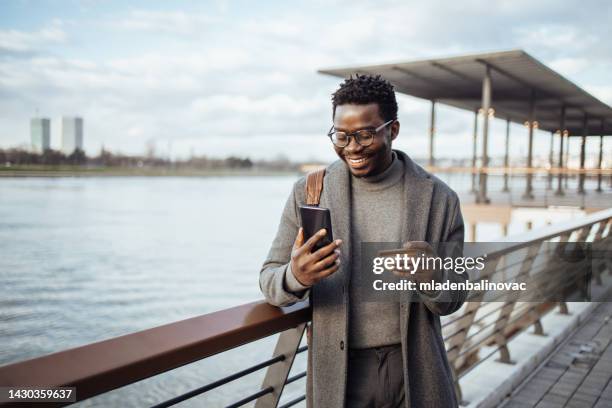 afroamerikanischer geschäftsmann mit smartphone auf der stadtstraße - premium with mobile stock-fotos und bilder