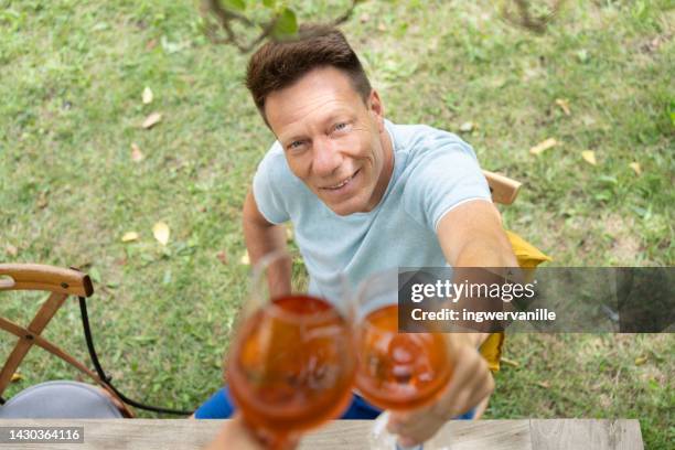 high angle view of mature man toasting with rose wine in a garden - single rose stockfoto's en -beelden