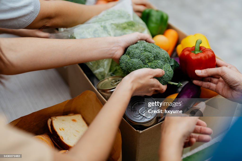 Voluntarios asiáticos empacando bienes y comestibles donados en el banco de alimentos