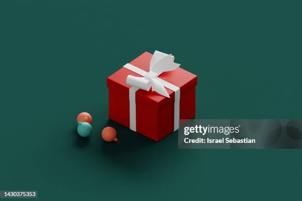 digitally generated close up image of a gift box and three christmas spheres placed on a plain green background. christmas greeting concept. - gift wrap stock-fotos und bilder