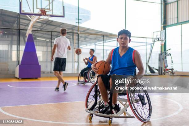basketball player in wheelchair holding ball on open ground. - wheelchair rugby stockfoto's en -beelden
