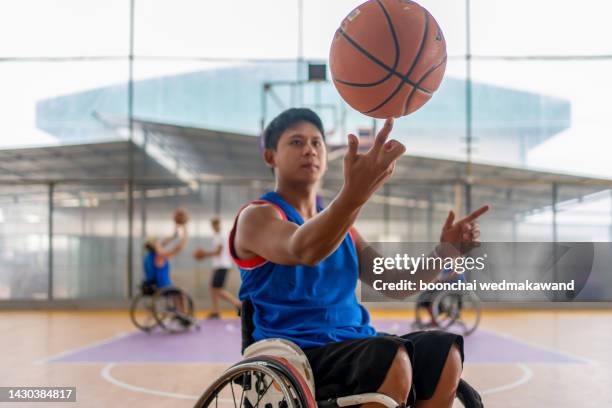 basketball player in wheelchair holding ball on open ground. - wheelchair rugby stockfoto's en -beelden