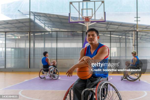 basketball player in wheelchair holding ball on open ground. - sia - fotografias e filmes do acervo