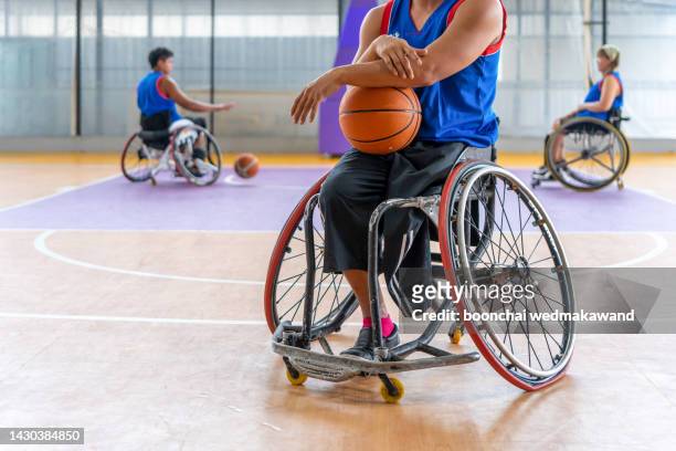 basketball player in wheelchair holding ball on open ground. - handicap photos et images de collection