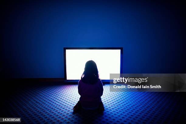 girl sitting in front of television - children screen stock-fotos und bilder