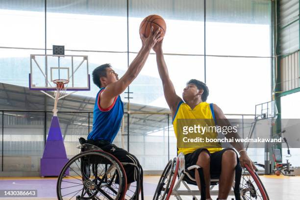 disabled sport men in action while playing indoor basketball at a basketball court - handicap photos et images de collection