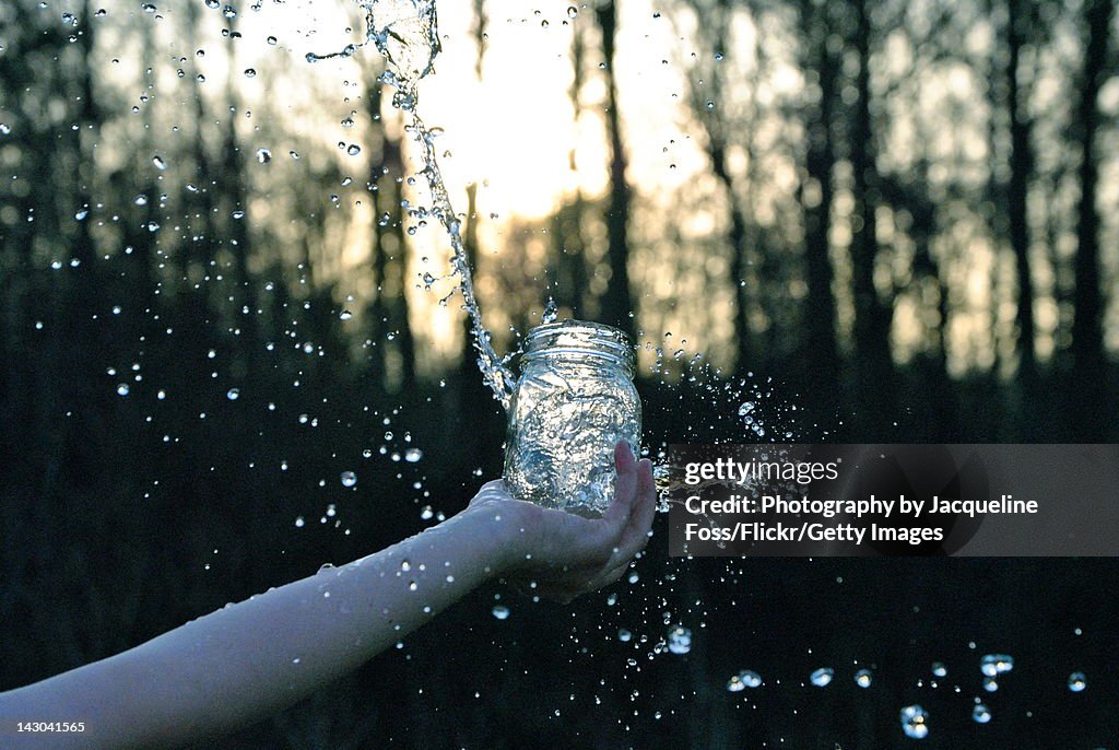 Human had splashing water from mason jar