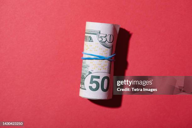 rolled up fifty dollar bills against red background - 50 dollar bill stock pictures, royalty-free photos & images