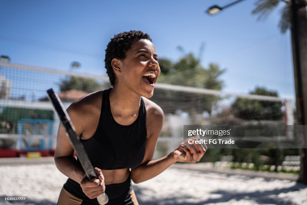 Excited woman celebrating during beach tennis match