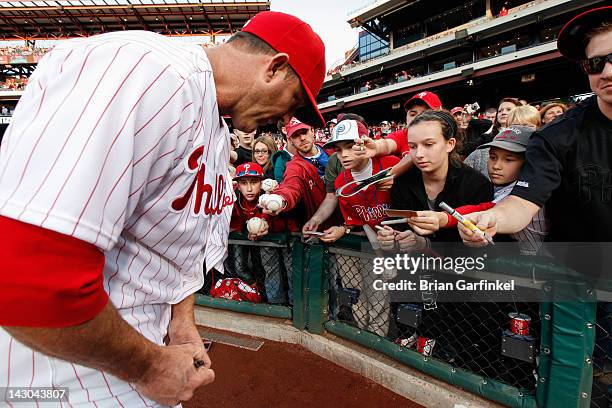Jim Thome of the Philadelphia Phillies signs a baseball for a fan before the game against the New York Mets at Citizens Bank Park on April 13, 2012...