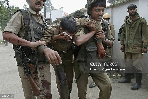 An Indian security officer is carried away by colleagues after being injured by an explosion while forces lay seige to a private home in Srinagar,...