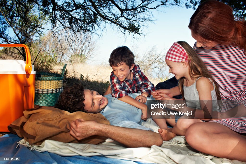 Family lying on picnic blanket together, smiling