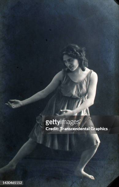 Photographic postcard of American dancer Isadora Duncan as she performs while on tour, circa 1905.