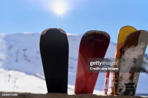 skis stretched out in the sunshine outside on a snowy mountain in the background is the radiant sun and clear blue sky. - ski closeup stock-fotos und bilder