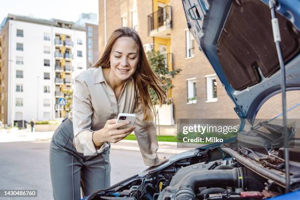 woman checking the engine on car and watching online instructions - diy disaster stock pictures, royalty-free photos & images