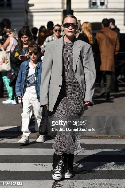 Guest is seen wearing a gray jacket and white knit dress and black bag outside the Miu Miu show during Paris Fashion Week S/S 2023 on October 04,...