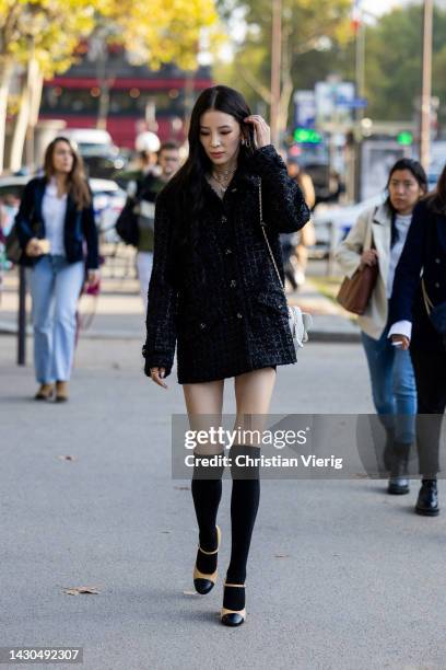 Irene Kim wears black jacket, skirt, over knee socks, white bag, brown black shoes outside Chanel during Paris Fashion Week - Womenswear...