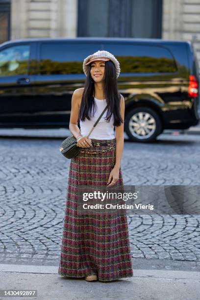 Yoyo Cao wears flat cap, checkered ling skirt, white shirt, black bag outside Chanel during Paris Fashion Week - Womenswear Spring/Summer 2023 : Day...