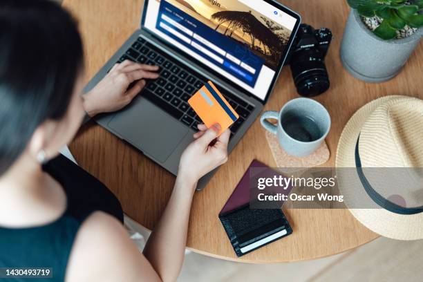 high angle view of young woman booking flight tickets online using laptop - hacer una reserva fotografías e imágenes de stock